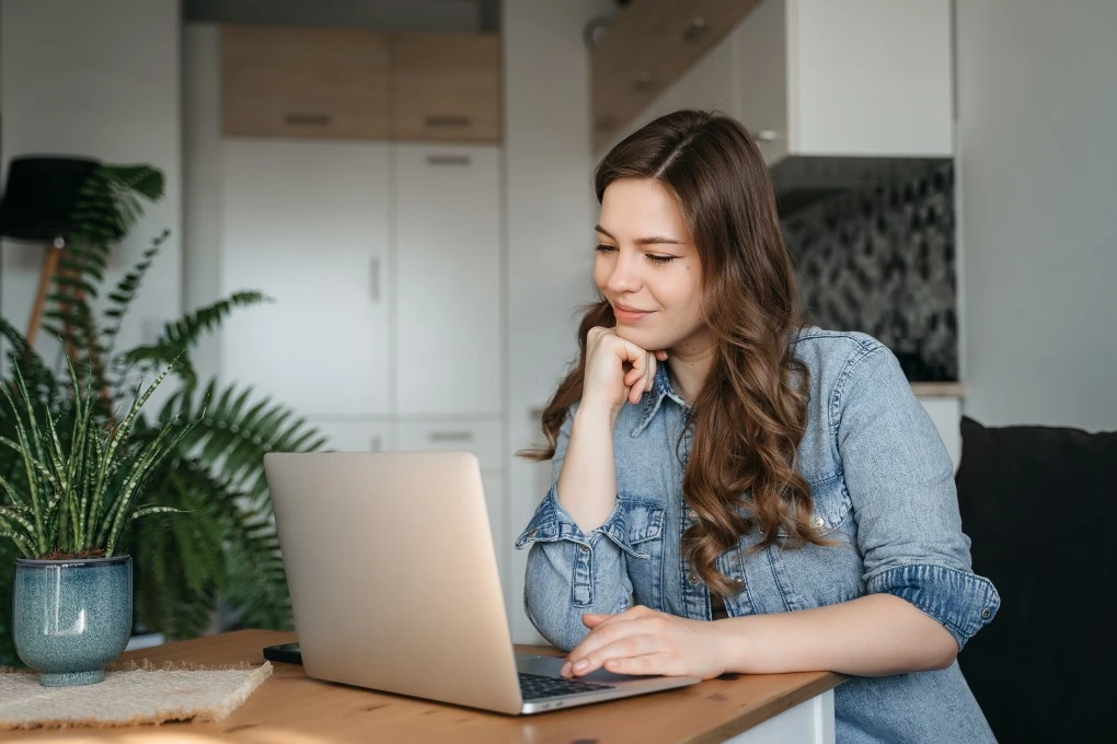 A woman smiling while looking at her laptop